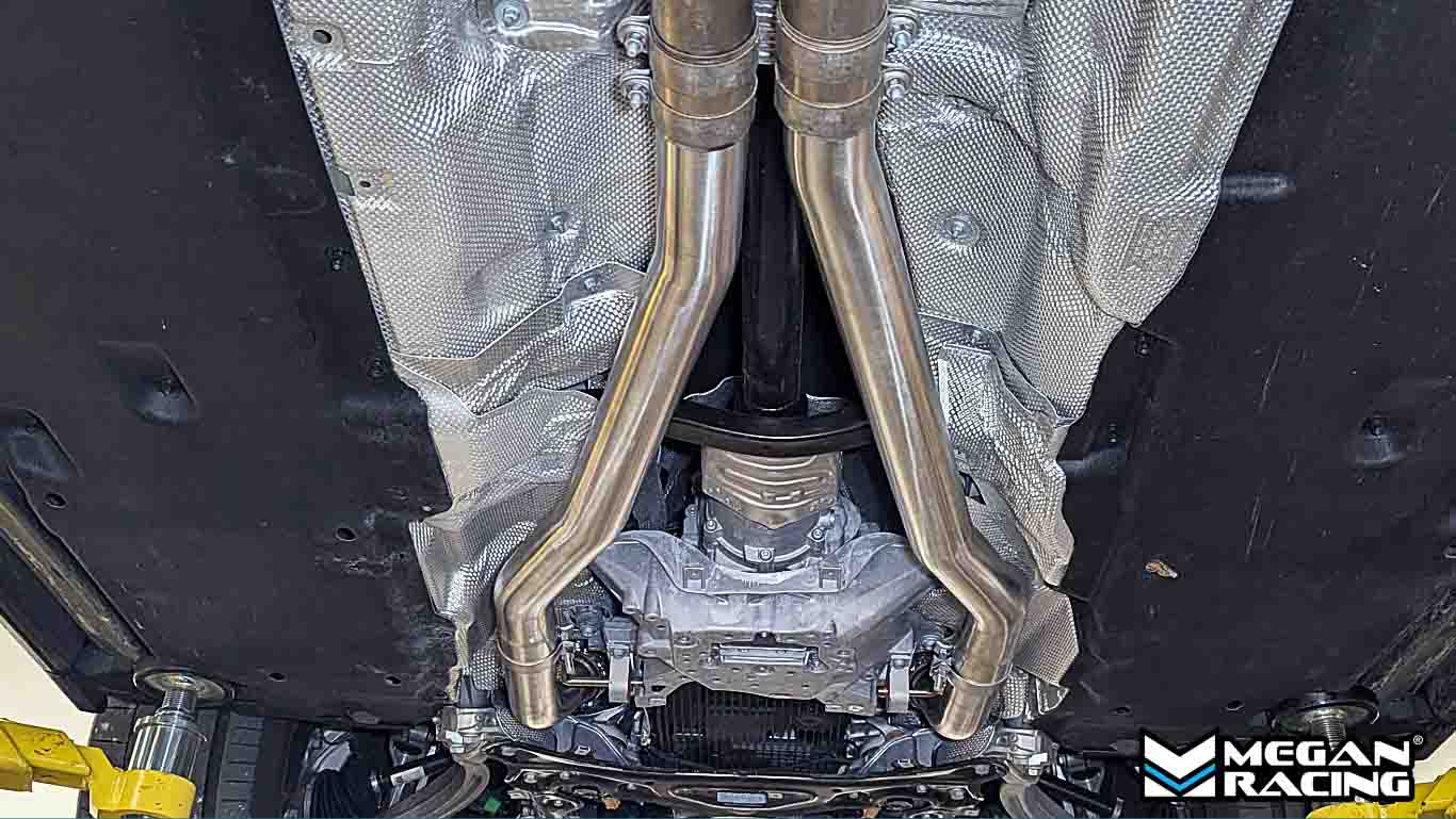 Close-up of a car's undercarriage Megan Racing branding Midpipe mid-pipe